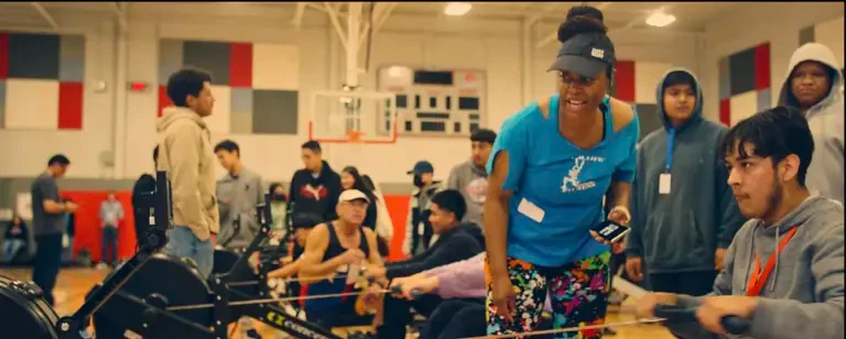 Group rowing in a busy gym setting.