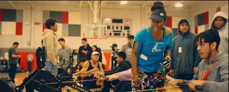 Group rowing in a busy gym setting.